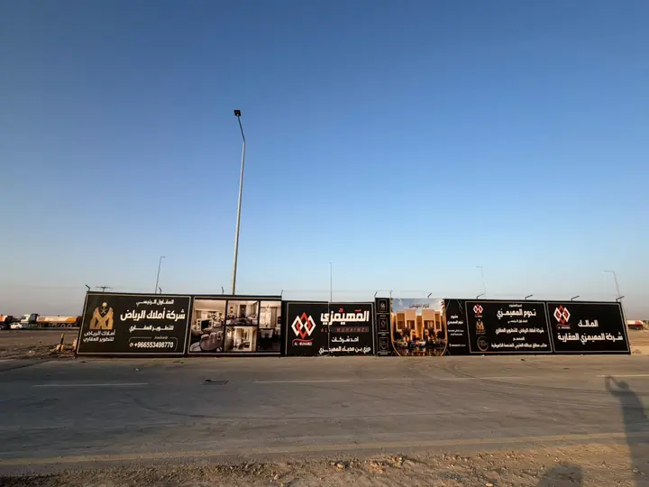 سور مشروع طويل عليه إعلانات على طريق